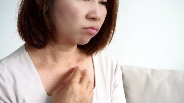 asian woman struggling with itching, rash, and red irritated skin on her neck and scratching due to sensitive skin conditions such as dryness, eczema, or allergic reactions