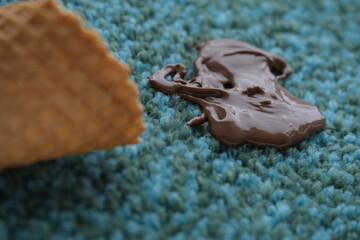 Spilled chocolate on a textured blue carpet in the living room. Daily stains concept on different surfaces