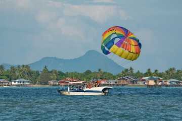 Semporna, Malaysia. On December 01, 2018, a tourist parachute flight by a guided boat over the sea waves.