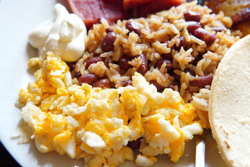 Traditional Costa Rican breakfast, rice and beans, called Gallo Pinto with eggs, tortilla, sausage and plantain.