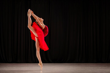 ballerina in a vibrant red dress performs a variation on stage. Capturing the grace and skill of...