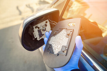Car maintenance with man in gloves replacing broken heated side mirror glass, focusing on safe auto repair process and installation tools, diy. Damaged miror heated glass. Selective focus
