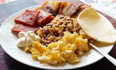 Traditional Costa Rican breakfast, rice and beans, called Gallo Pinto with eggs, tortilla, sausage and plantain.