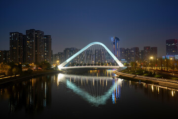 Fototapeta premium The glowing bridges and city skyline on the river at night, Chengdu, China