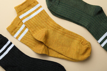 Different soft socks on beige background, top view