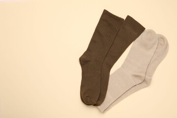 Pairs of stylish socks on beige background, top view. Space for text