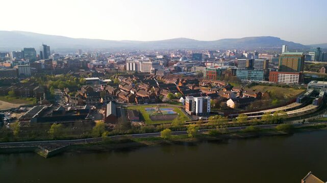 Reversing aerial shot of the River Lagan in Belfast on a bright, sunny summer day. The camera takes in the Lower Ormeau area, Ormeau Park and the river. Filmed in 4K, 60fps and with Rec709 Color.
