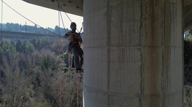 Rope access technician performing maintenance on bridge pylon