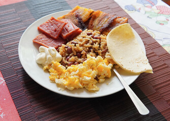 Traditional Costa Rican breakfast, rice and beans, called Gallo Pinto with eggs, tortilla, sausage and plantain.