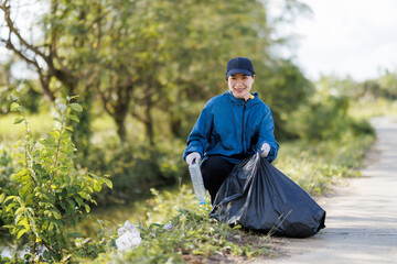 Fototapeta premium An Asian young woman volunteering to clean up trash along the canal.