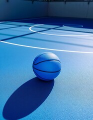 blue basketball rests on a sunlit outdoor court