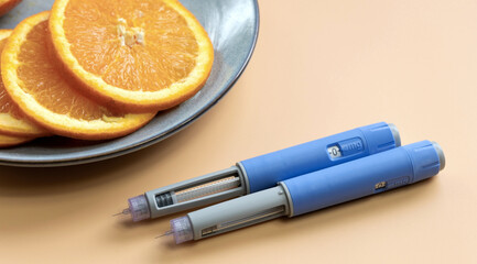 Two Insulin injection pen for diabetics and weight loss and plate with orange