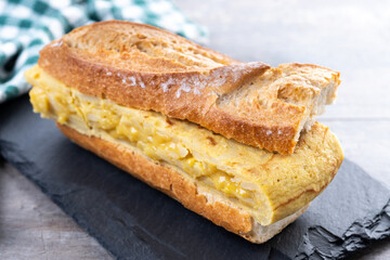 Spanish potato omelette sandwich on wooden table. Bocadillo de tortilla