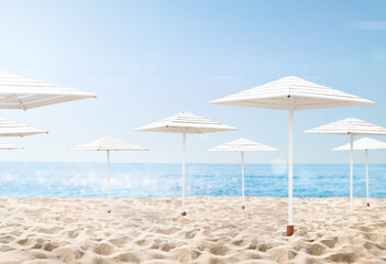 many beach umbrellas in the sand with the sea in the background