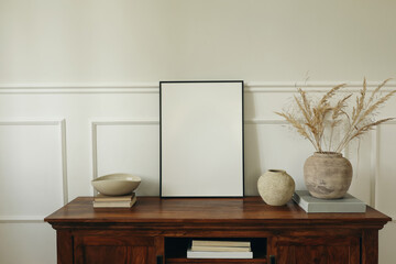 Elegant living room. Mahogany wooden cabinet dresser. Empty picture mock up poster frame. Clay...