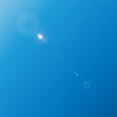 The sun, located at the top of a clear blue sky, emits a bright light, creating a lens flare effect with soft rays directed downwards.