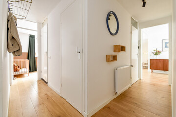 A stylish and minimalistic interior hallway featuring natural light, wooden flooring, and modern furniture elements. The space emphasizes simplicity and functionality.