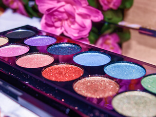 Close-up of glitter makeup palette with soft floral decor in background, ideal for beauty blogs, skincare ads, social media, the visual elements of cosmetic products.