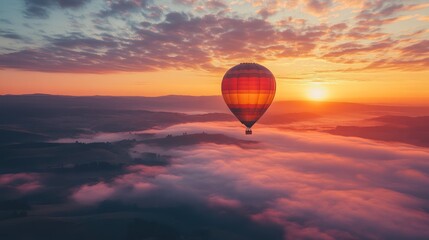 Obraz premium A colorful hot air balloon floats above a landscape of rolling hills shrouded in morning mist.