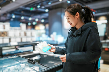 Young Woman Selecting Skincare Products in Modern Retail Space