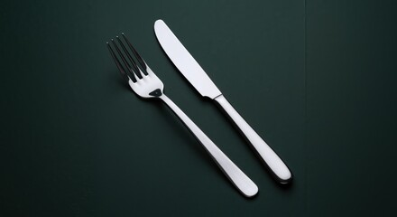 Silver fork and knife on dark green background  