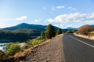 Double lines on bend of mountain road beside lake