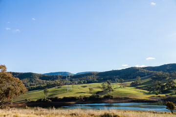 Jounama Pondage and sunlit hill with power lines coming from Tumut 3 powerstation