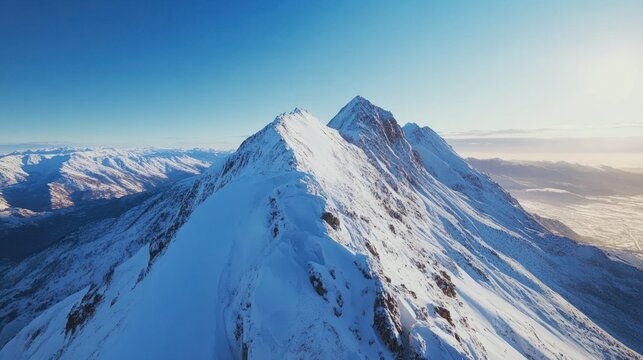 Stunning aerial view of snow-capped mountains under a clear blue sky, showcasing nature's beauty and majesty.