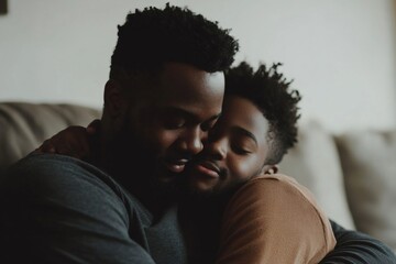 Obraz premium Portrait of black father and son hugging on couch