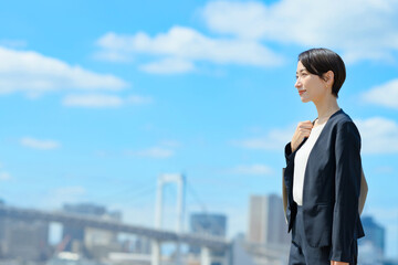 青空をバックに立つビジネスウーマン