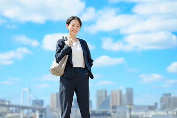 青空をバックに立つビジネスウーマン