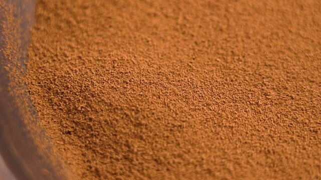 Ground chicory powder falling into a rotating eco friendly wooden bowl in slow motion. Healthy Instant drink ingredient. Macro shot