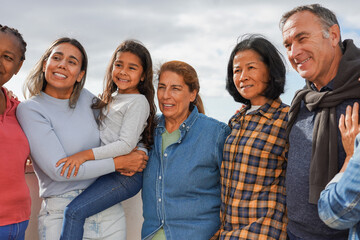 Group of multi generational people having fun hugging each other outdoor - Multiracial friends taking a picture together at house rooftop dinner