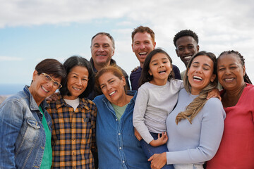 Group of multiracial friends smiling on camera outdoor - Multi generational people hugging each other - Community, social inclusion and lifestyle concept