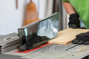 Senior man engaged in woodworking hobby using a table saw in his garage during the afternoon. - series