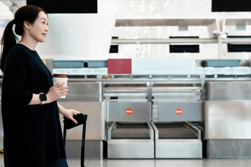 Woman at Airport Check-in Desk with Coffee and Luggage