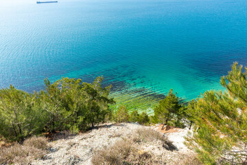 Panoramic view of the wild narrow beach Blue Abyss in Gelendzhik, Russia under a steep white cliff...