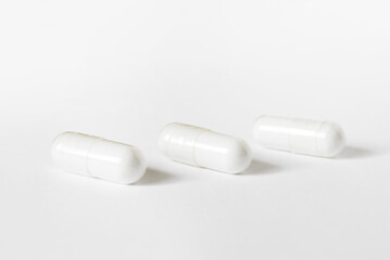 Three white capsules on white background. different pills and tablets, medication pharmaceuticals health