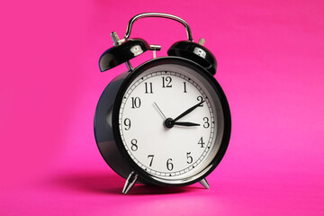 One black alarm clock on color background
