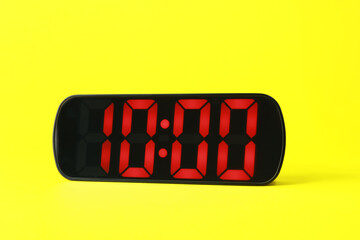 Digital alarm clock showing 10:00 o'clock on yellow background