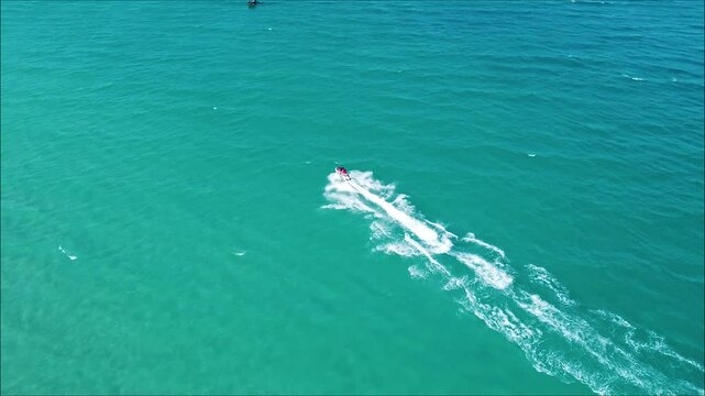 Aerial view of the jet ski in clear blue water on summer sunny day. Top drone view of fast floating motorboat in ocean.