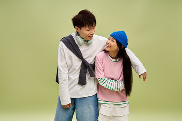 Obraz premium Charming couple shares joyful moments in stylish outfits against a soft green backdrop