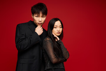 Chic couple displays love and romance against a vibrant red backdrop in a stylish setting