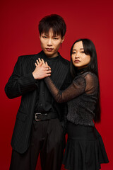 Fashionable couple expressing their love in a vibrant studio setting with a bold red backdrop