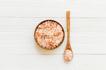 Coarse pink salt in wooden bowl and spoon and spilled salt. Cooking or spa concept