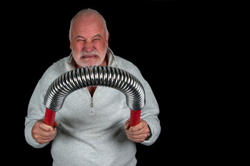 A 68-year-old man bends the professional-grade spring with visible effort. Teeth gritted, muscles tensed, showing no mercy to the steel. A picture of pure willpower and strength.