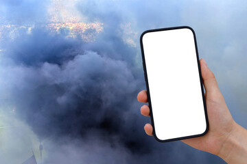 Cell phone with transparent screen in human hands. In the background, dense, blue clouds of smoke over a soccer stadium of celebrating fans.