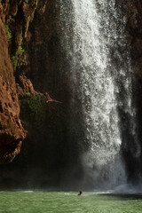 Moroccan young man  jumps from the high rock into the water under a waterfall Ouzoud.
