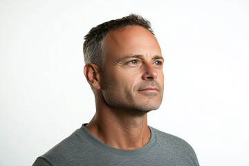 Obraz premium Portrait of a confident and thoughtful mature man with gray hair looking into the distance, wearing a casual gray shirt, captured against a bright neutral background in a minimalist style.