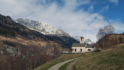 Catholic church in the Swiss Alps with mountains in the background in early spring